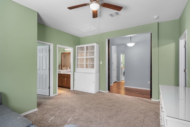 carpeted bedroom featuring ceiling fan, connected bathroom, and washer / clothes dryer