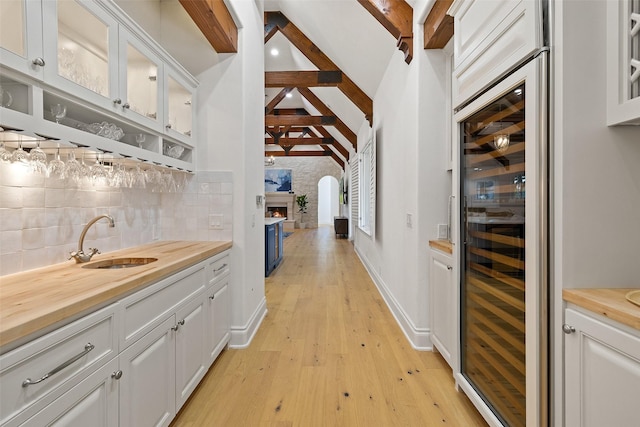 bar with sink, white cabinetry, decorative backsplash, and butcher block countertops