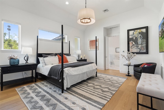 bedroom featuring ensuite bathroom, lofted ceiling, and light wood-type flooring