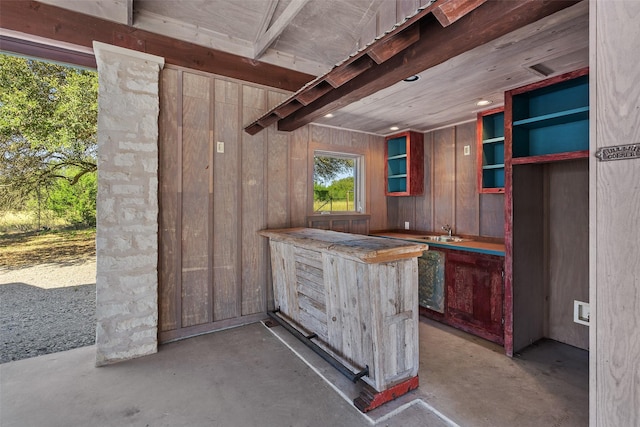 bar featuring sink, wood walls, and concrete flooring