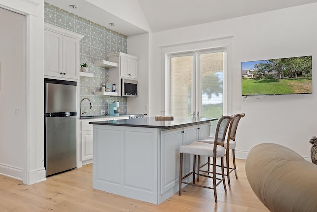 kitchen featuring backsplash, white cabinets, light wood-type flooring, and appliances with stainless steel finishes