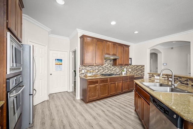 kitchen with crown molding, appliances with stainless steel finishes, sink, light stone counters, and light hardwood / wood-style floors