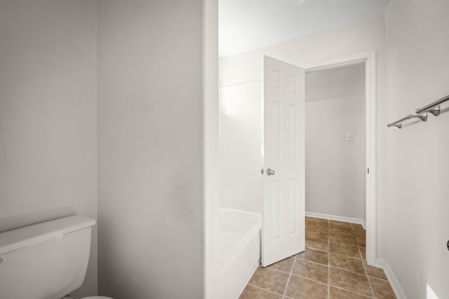 bathroom with toilet and a tub to relax in