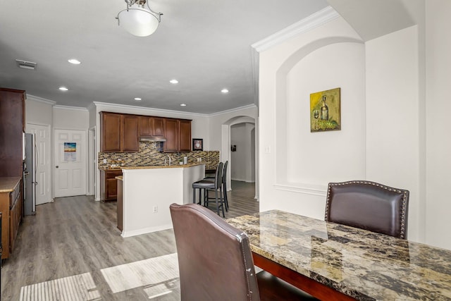 dining space with light hardwood / wood-style flooring and ornamental molding