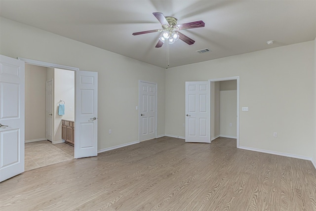 unfurnished bedroom featuring light wood-type flooring, ensuite bathroom, and ceiling fan