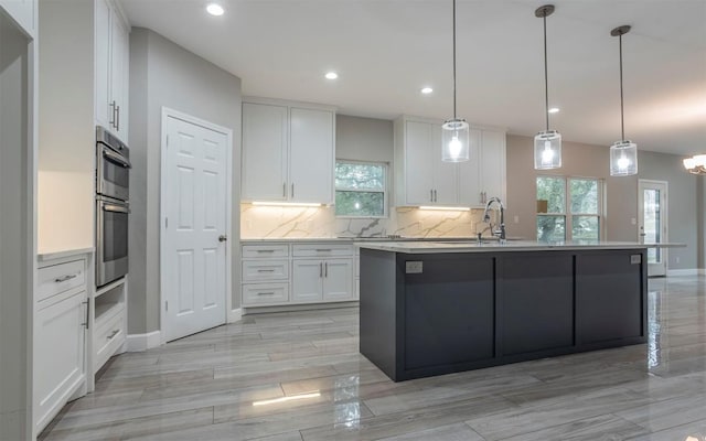 2718 Leslie Ln, San Marcos, TX 78666 - kitchen featuring white cabinets, tasteful backsplash, a kitchen island with sink, plenty of natural light, and recessed lighting