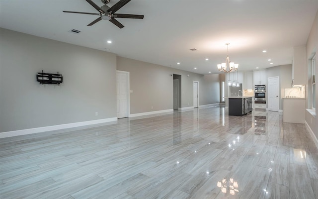 unfurnished living room featuring sink and ceiling fan with notable chandelier