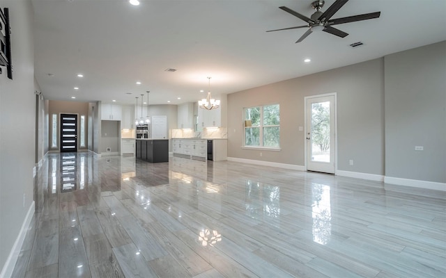 unfurnished living room with ceiling fan with notable chandelier