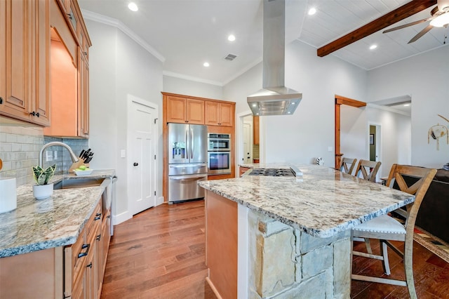 kitchen with light stone countertops, appliances with stainless steel finishes, island exhaust hood, beamed ceiling, and a breakfast bar area