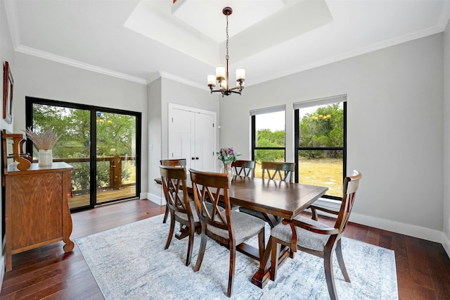 dining area with crown molding, dark hardwood / wood-style flooring, a chandelier, and a raised ceiling