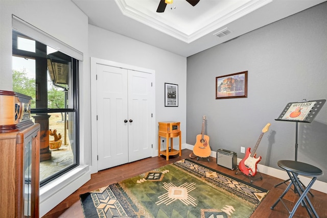 game room featuring ornamental molding, dark wood-type flooring, ceiling fan, and a raised ceiling