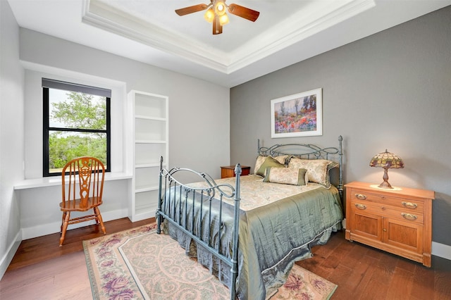 bedroom featuring ceiling fan, ornamental molding, a tray ceiling, and dark hardwood / wood-style flooring