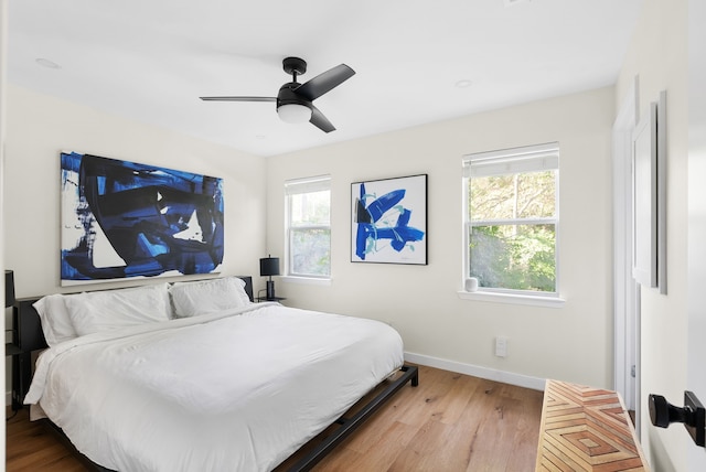 bedroom with ceiling fan, multiple windows, and hardwood / wood-style flooring