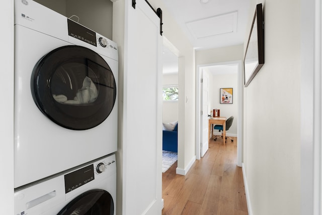 laundry area featuring stacked washer and clothes dryer and light hardwood / wood-style floors