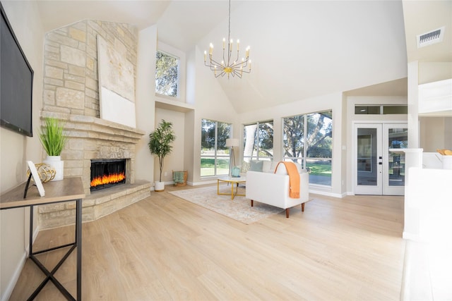 interior space with a notable chandelier, a stone fireplace, and french doors