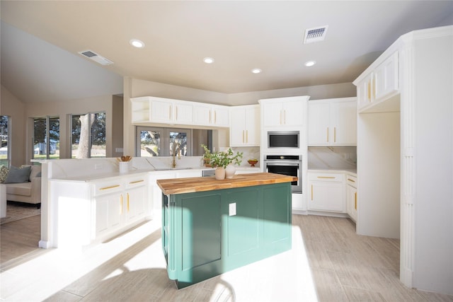 kitchen with decorative backsplash, white cabinets, a center island, and oven