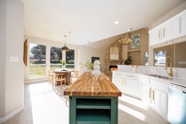 kitchen with dishwasher, white cabinetry, sink, a kitchen island, and decorative light fixtures