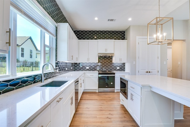 kitchen featuring sink, stainless steel appliances, hanging light fixtures, and white cabinets