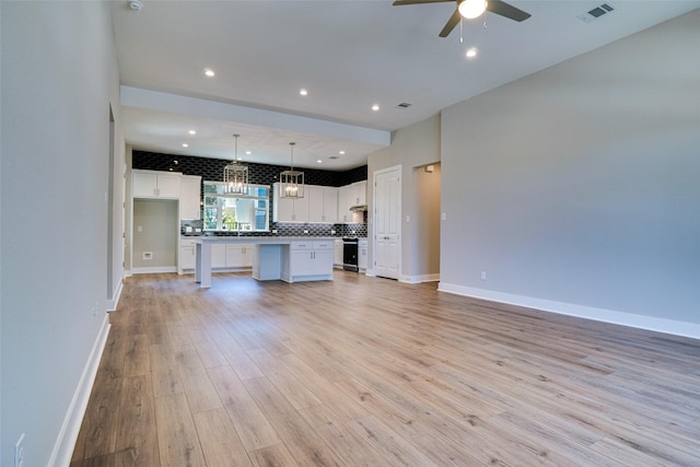 kitchen with light hardwood / wood-style flooring, hanging light fixtures, white cabinetry, ceiling fan with notable chandelier, and a center island