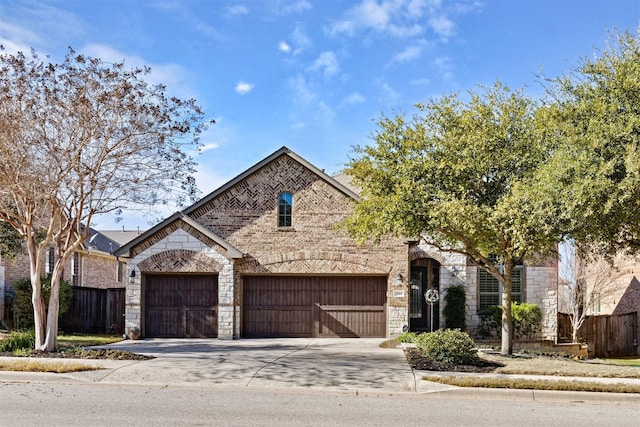 french country home with concrete driveway, brick siding, stone siding, and fence