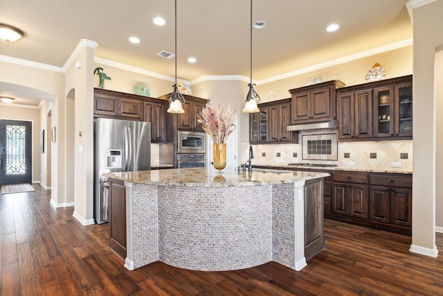 kitchen with dark brown cabinetry, glass insert cabinets, decorative light fixtures, stainless steel appliances, and a sink