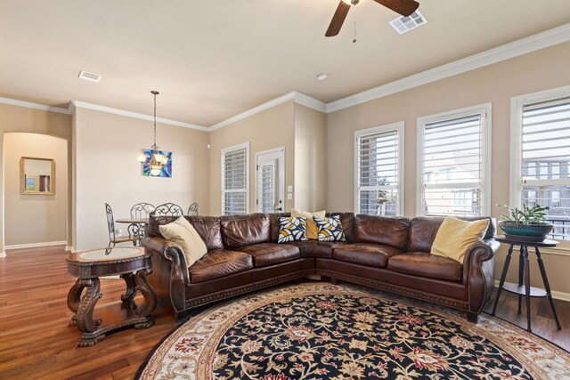 living room with ornamental molding, wood finished floors, visible vents, and baseboards