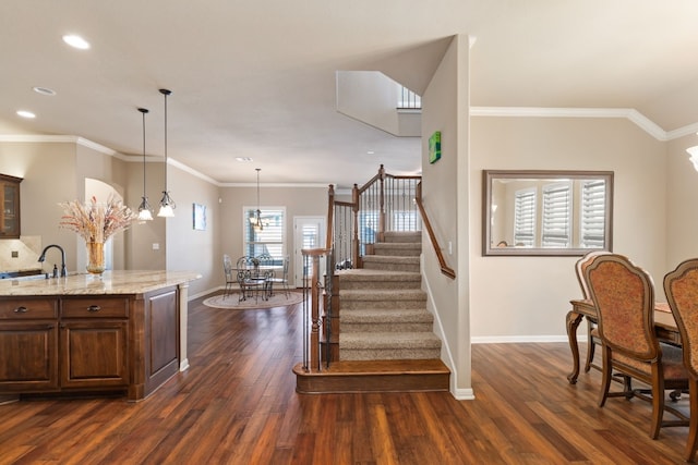 stairs featuring a notable chandelier, recessed lighting, wood finished floors, baseboards, and ornamental molding