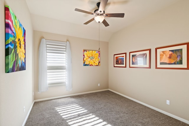 carpeted empty room with baseboards, vaulted ceiling, and a ceiling fan