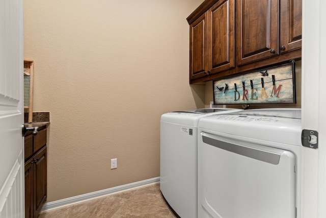 clothes washing area with cabinet space, independent washer and dryer, baseboards, and light tile patterned floors