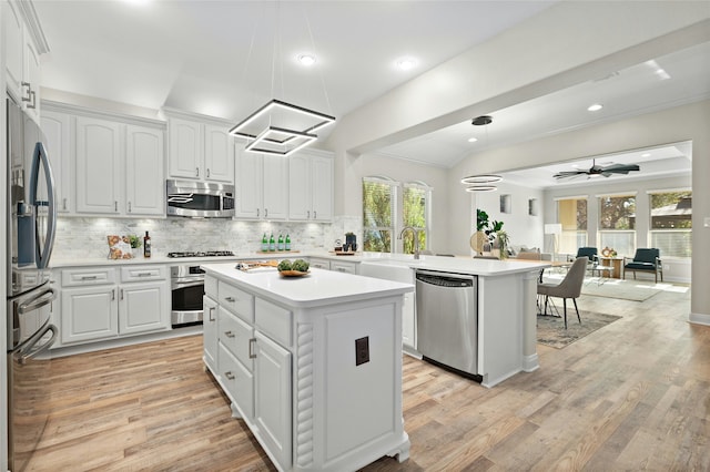 kitchen featuring kitchen peninsula, white cabinetry, a center island, and appliances with stainless steel finishes