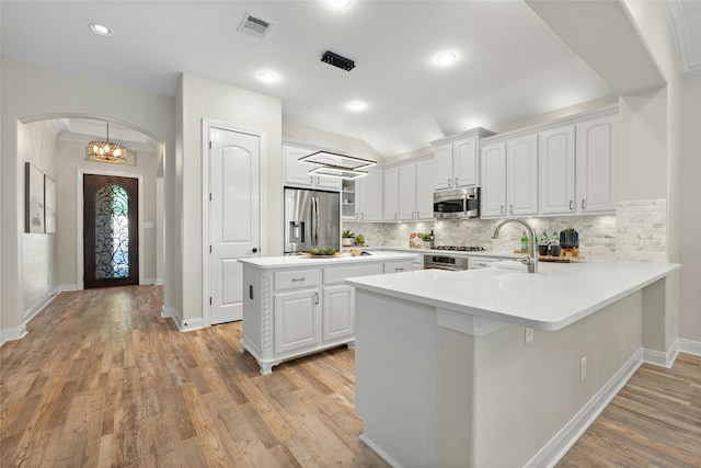 11716 Shadestone Ter, Austin, TX 78732 - kitchen featuring appliances with stainless steel finishes, arched walkways, a peninsula, white cabinets, and backsplash