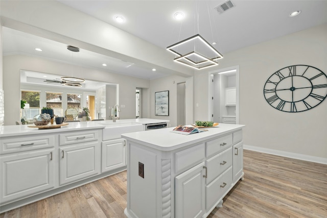 kitchen featuring a center island, light hardwood / wood-style floors, white cabinets, decorative light fixtures, and sink