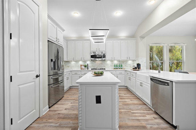 kitchen featuring a kitchen island, white cabinetry, stainless steel appliances, decorative backsplash, and hanging light fixtures