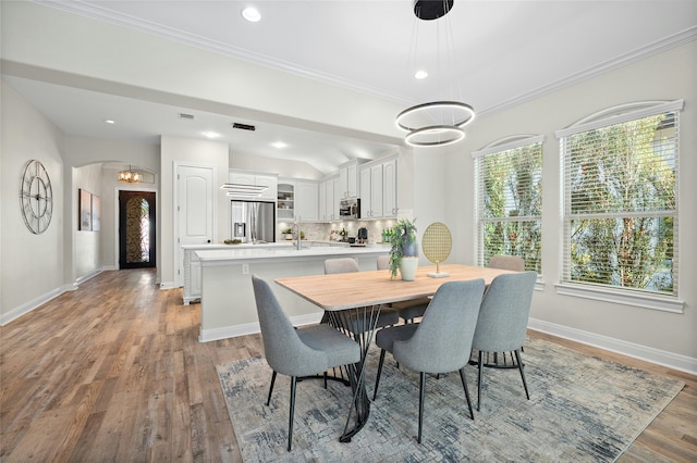 dining area featuring a wealth of natural light, light hardwood / wood-style flooring, crown molding, and an inviting chandelier