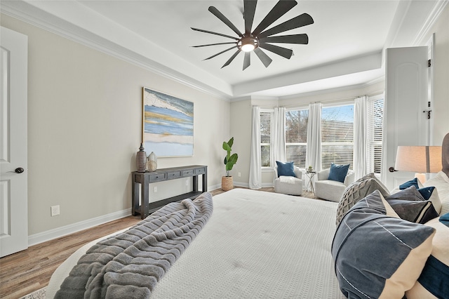 bedroom featuring light hardwood / wood-style flooring, a tray ceiling, ceiling fan, and ornamental molding