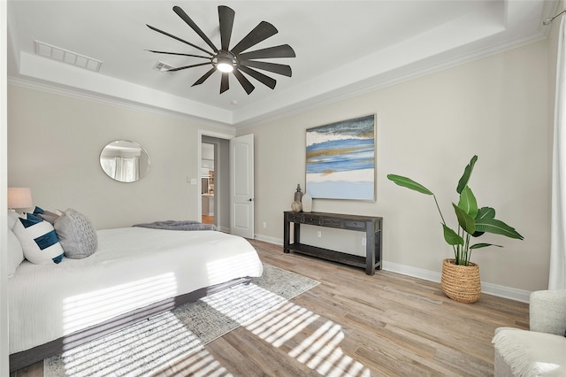 bedroom featuring crown molding, light wood-type flooring, ceiling fan, and a raised ceiling