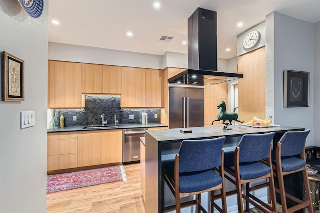 kitchen with sink, light hardwood / wood-style flooring, stainless steel appliances, island exhaust hood, and light brown cabinetry