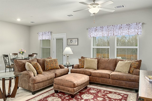 living room featuring light wood-style floors, ceiling fan, and visible vents