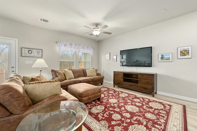 living room with baseboards, a ceiling fan, visible vents, and light wood-style floors