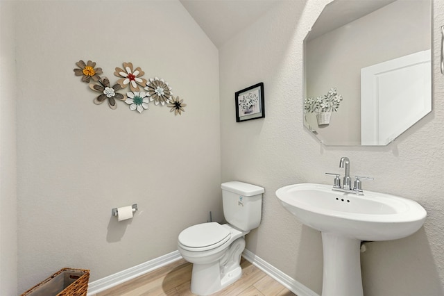 bathroom with hardwood / wood-style flooring, toilet, and vaulted ceiling