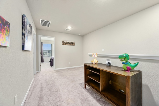 hall with light carpet, baseboards, and visible vents