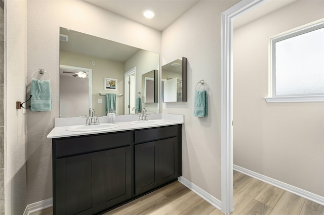 full bathroom with double vanity, baseboards, a sink, and wood finished floors