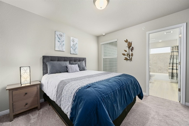 carpeted bedroom featuring visible vents, ensuite bath, and baseboards