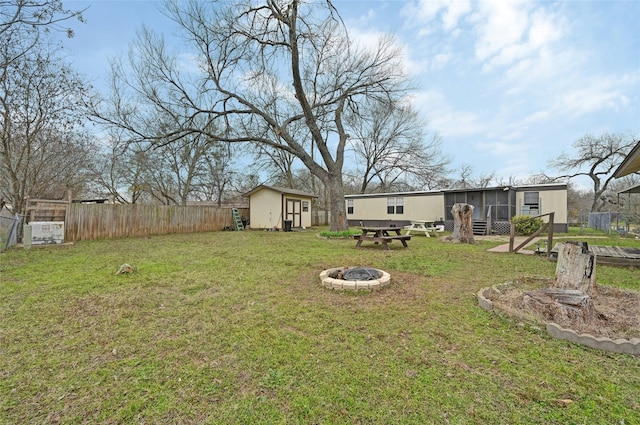 view of yard with a sunroom, a storage shed, and a fire pit