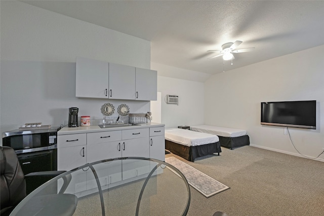 kitchen with sink, carpet, a textured ceiling, an AC wall unit, and lofted ceiling