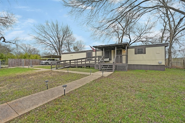 manufactured / mobile home featuring a deck, a front yard, and a carport