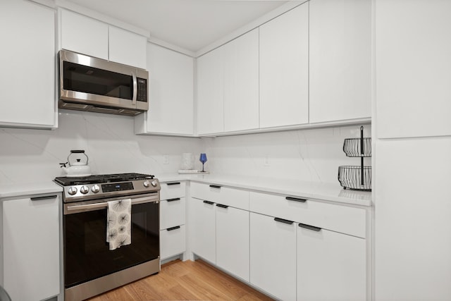 kitchen with light wood-type flooring, white cabinetry, and appliances with stainless steel finishes