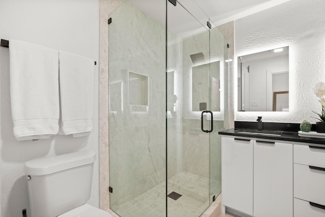 bathroom featuring toilet, a shower with door, and vanity