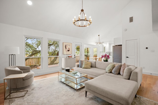 living room with high vaulted ceiling, light hardwood / wood-style flooring, and a chandelier