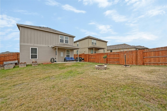 rear view of property featuring a yard and an outdoor living space with a fire pit